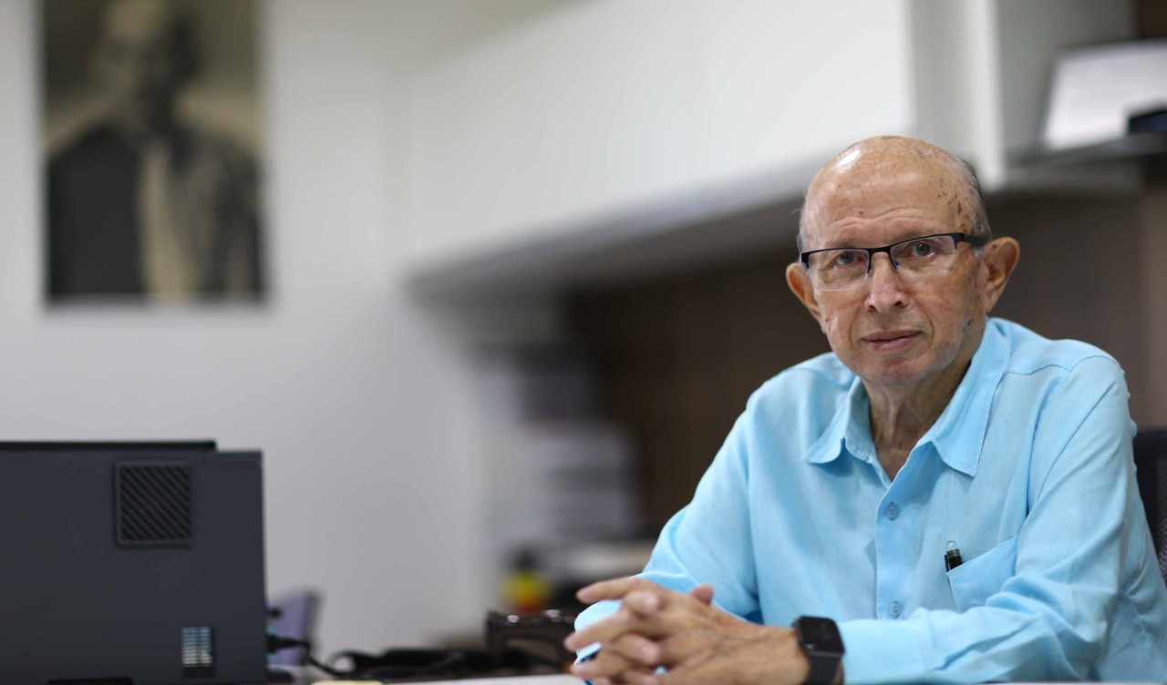 professor roberto cláudio posa para a foto em sua mesa de trabalho